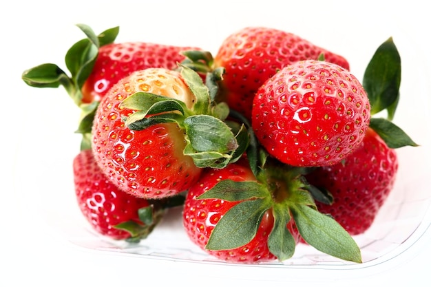 Reife Erdbeeren in einer Kunststoffverpackung auf weißem Hintergrund Köstliche frische Beeren in einem Behälter zum Verkauf an Kunden Lebensmittel frisch halten Gesunde Lebensmittel, Vitamine und Spurenelemente