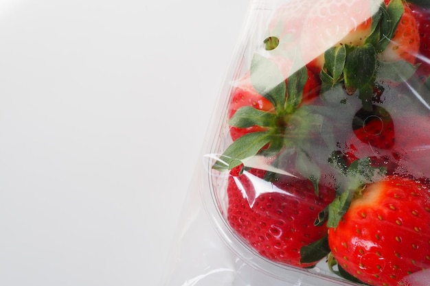 Reife Erdbeeren in einer Kunststoffverpackung auf weißem Hintergrund Köstliche frische Beeren in einem Behälter zum Verkauf an Kunden Lebensmittel frisch halten Gesunde Lebensmittel, Vitamine und Spurenelemente