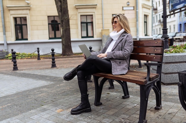 Reife Frau, die am Laptop arbeitet, während sie im Stadtpark sitzt