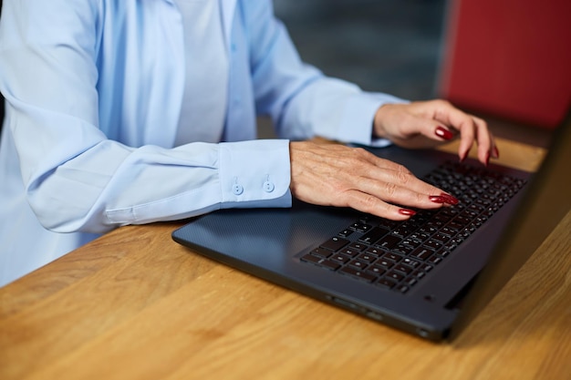 Reife Frau, die auf modernen Technologien des Laptops tippt