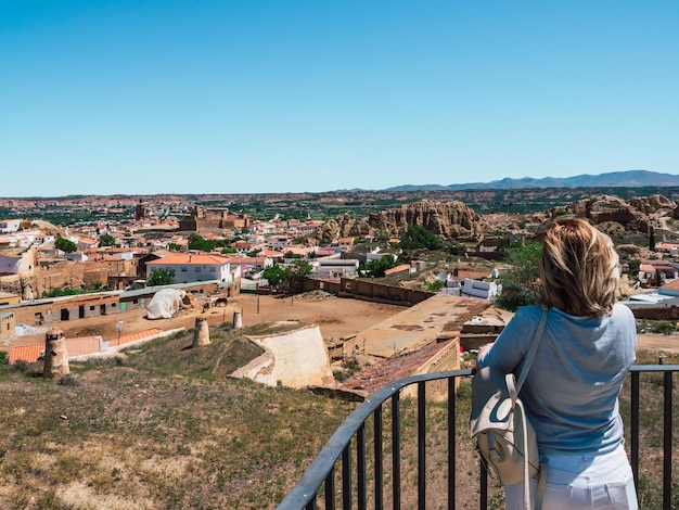 Reife Frau, die einen Panoramablick auf die Landschaft am Aussichtspunkt der Höhlen von Guadix beobachtet