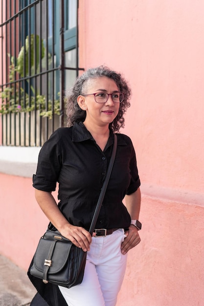 Foto reife frau, die gegen rosa wand steht