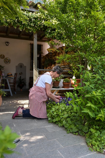 Reife Frau, die im Garten ihres Hauses arbeitet, vertikale Aufnahme