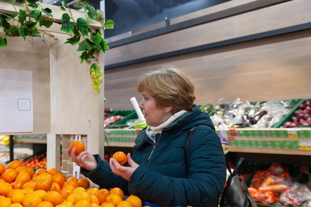 Reife Frau, die im Laden einkauft und Obst und Gemüse auswählt