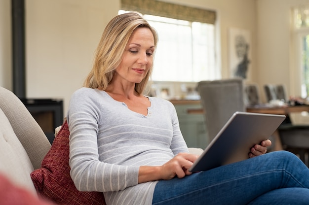 Reife Frau, die mit digitalem Tablett entspannt