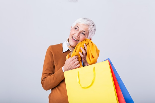 Reife Frau, die Seidenschal gegen ihr Gesicht hält und lächelt.