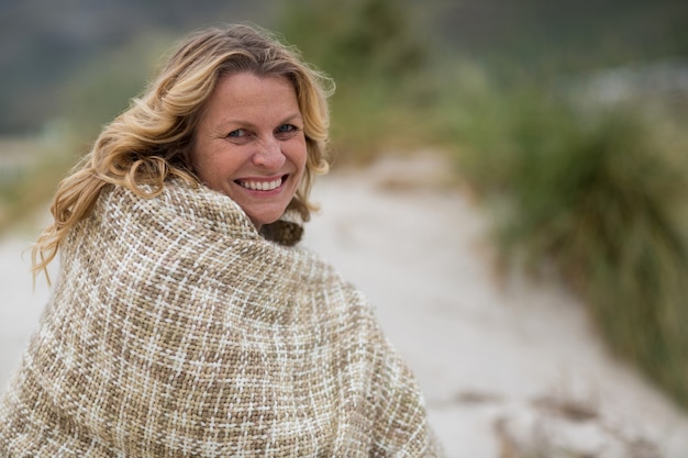 Reife Frau in Schal am Strand gewickelt