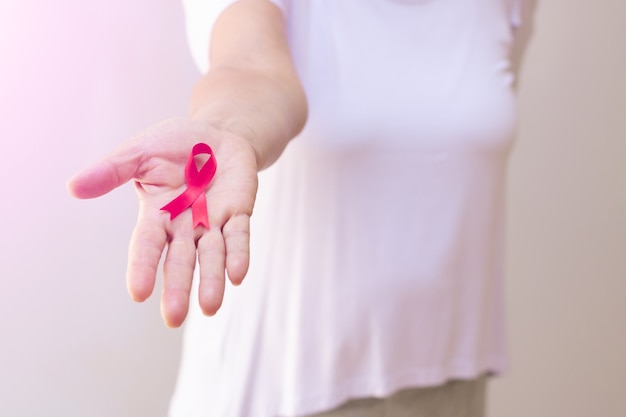 Reife Frau mit einem rosa Band, isoliert auf weiss. Bild des Brustkrebs-Aufklärungsmonats.