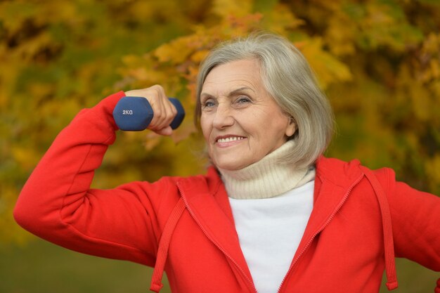 Reife Frau mit Hanteln im Herbstpark