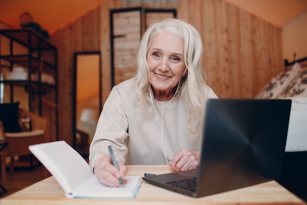 Reife Frau mit Laptop, die am Tisch sitzt und im Glamping-Campingzelt spricht. Modernes Urlaubs-Lifestyle-Konzept.