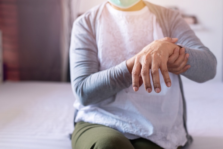 Foto reife frau mit parkinson-symptomen zur hand