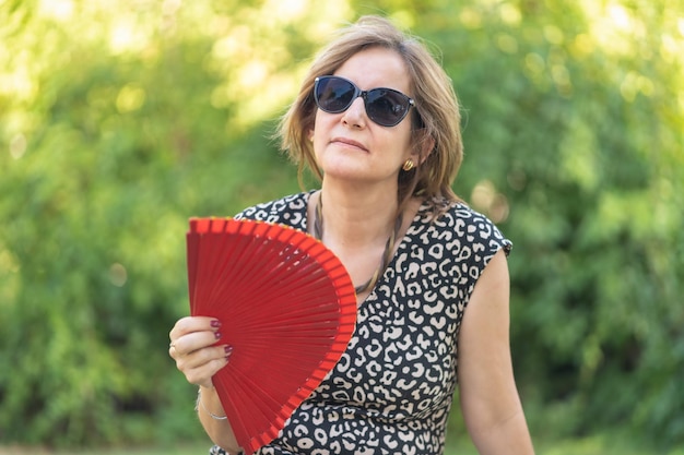 Reife Frau mit Symptomen der Menopause mit starken Hitzewallungen und Fächeln