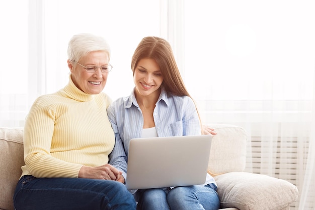 Reife Frau und Tochter mit Laptop Fotos ansehen