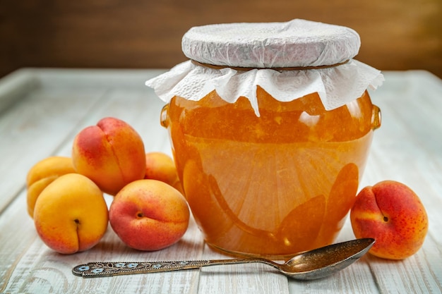 Reife frische Aprikosen und Aprikosenmarmelade in einem Glas auf Holzhintergrund Selektive Fokussierung auf gesunde Ernährung