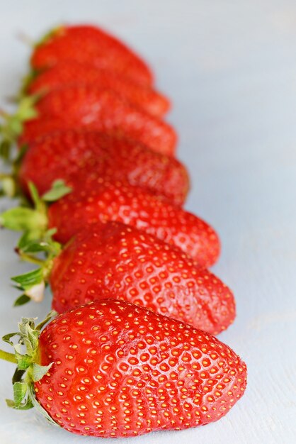 Reife frische Bio-Erdbeeren an einer blauen Wand, Platz für Text. Saftige Sommerbeeren.