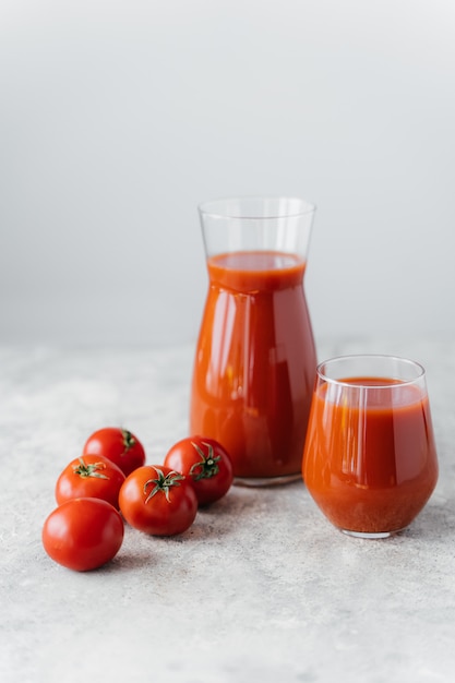 Reife frische rote Tomaten nahe zwei Gläsern zusammengedrücktem geschmackvollem Tomatensaft