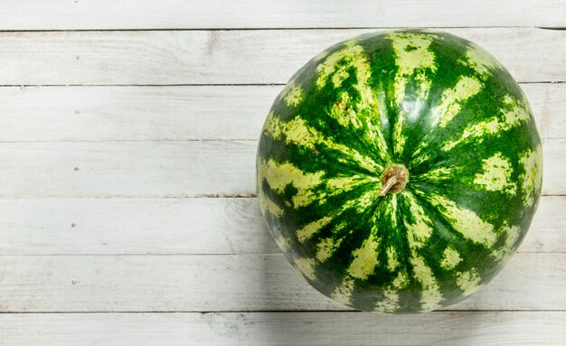 Reife frische Wassermelone auf weißem Holztisch.