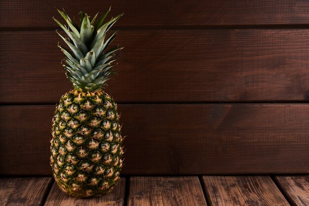 Reife ganze Ananas isoliert auf Holztischhintergrund mit Kopierraum