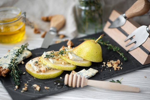 Reife gelbe Birne mit Dor Blauschimmelkäse, Honig und Walnüssen auf einem Käsebrett