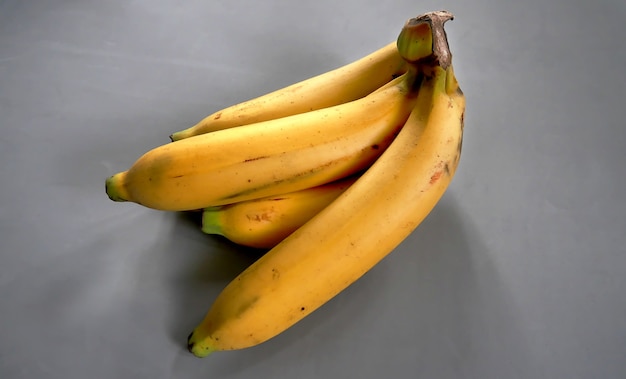 Reife goldene Bananen auf grauem Hintergrund geerntet