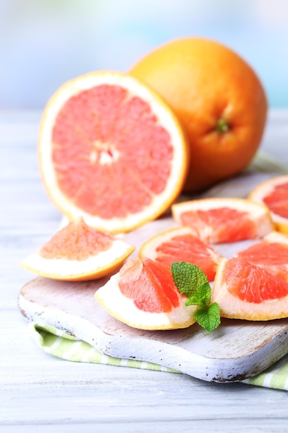 Reife Grapefruits auf einem Schneidbrett auf einem Holztisch auf hellem Hintergrund