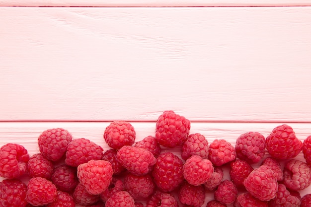 Reife Himbeeren auf rosa hölzernem Hintergrund