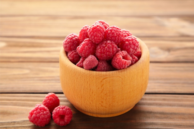 Reife Himbeeren in der Holzschale auf braunem Hintergrund