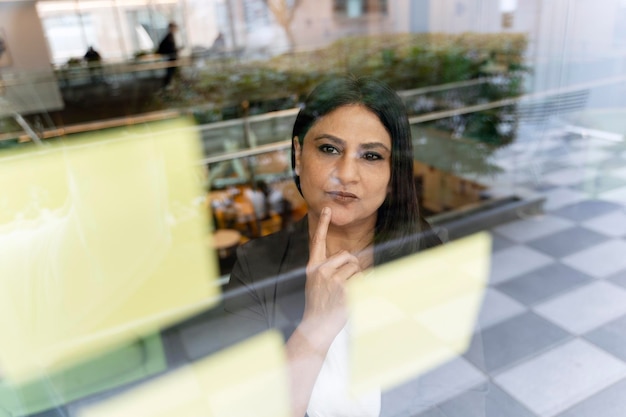 Reife indische Geschäftsfrau Planungsprojekt mit Sticks Notizen auf Glaswand mit Idee Scrum