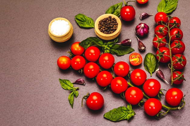 Reife Kirschtomaten und Gewürze auf einem Steinhintergrund