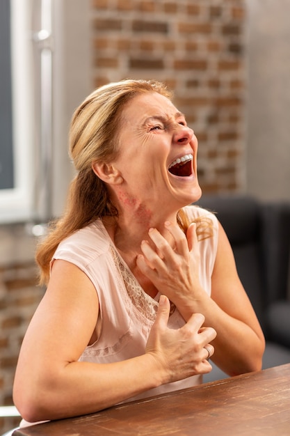 Reife kranke Frau schreit wegen Schmerzen und Hautausschlag nach dem Verzehr allergischer Lebensmittel eating