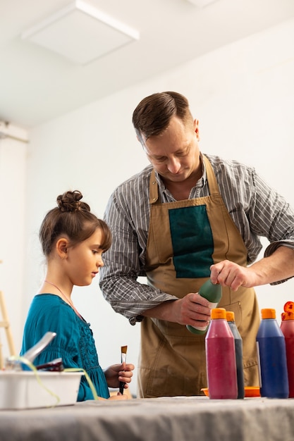 Reife Kunstlehrerin, die braune Schürzenöffnungsfarbe für Mädchen trägt