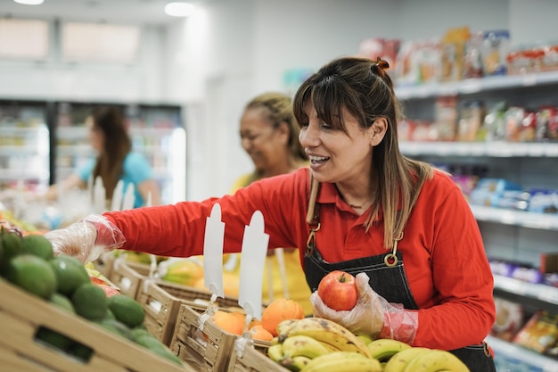 Reife lateinamerikanische Frau, die in einem Supermarkt arbeitet und Früchte arrangiert