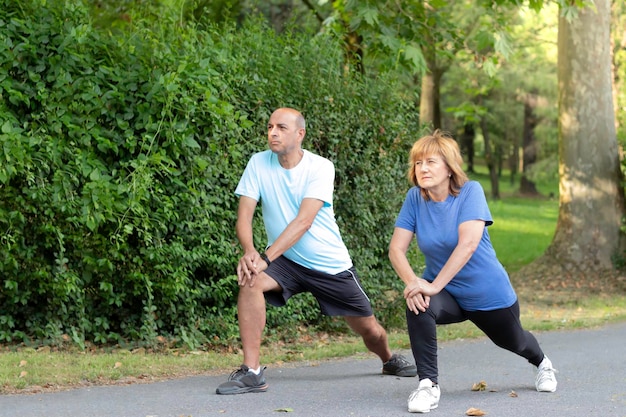 Reife Männer und Frauen, die sich als Paar in einer grünen natürlichen Umgebung des Stadtparks ausdehnen