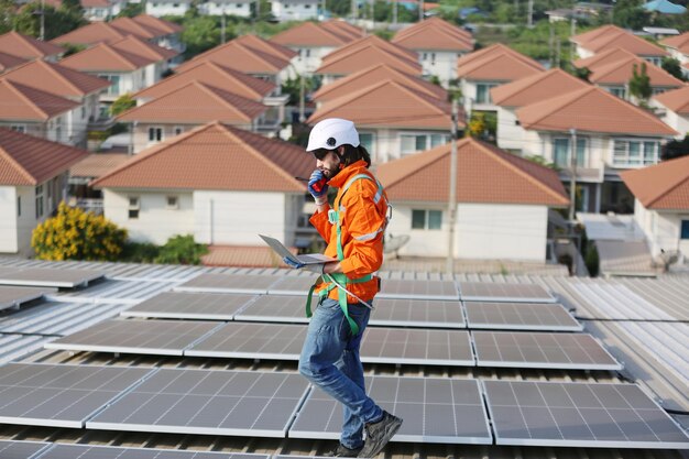 Reife männliche Ingenieure gehen entlang der Reihen von Photovoltaikmodulen auf dem Dach einer Solaranlage
