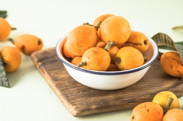 Reife Mispelfrucht Eriobotrya japonica und grüne Mispelblätter auf Holztisch Draufsicht