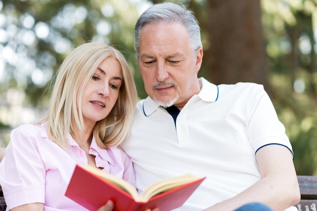 Reife Paare, die ein Buch im Park lesen