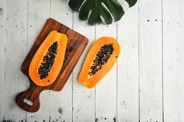 Foto reife papaya auf einem hölzernen schneidebrett am tisch