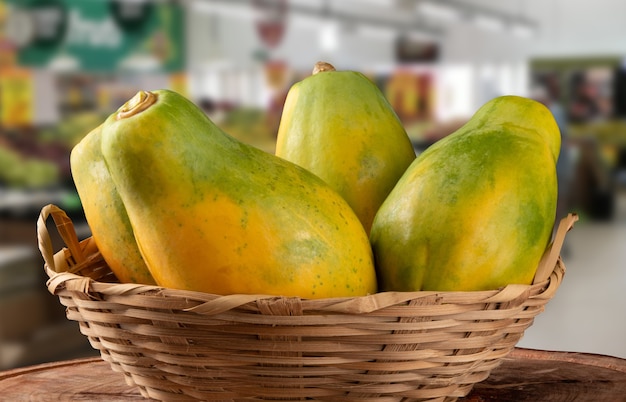 Reife Papaya-Frucht im Korb auf unscharfer Oberfläche.