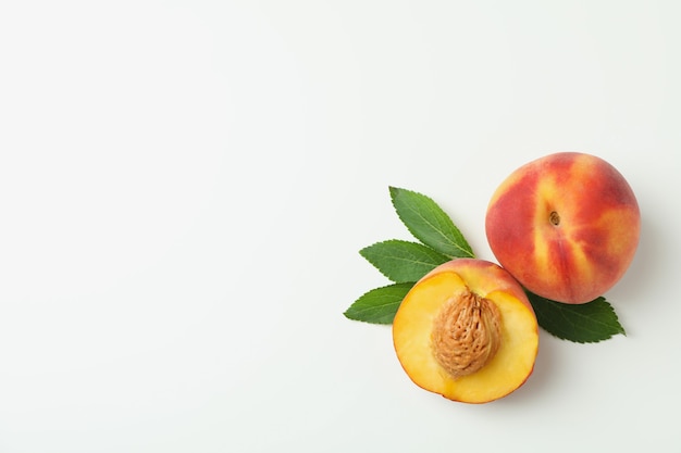 Reife Pfirsichfrüchte mit Blättern auf weißem Hintergrund