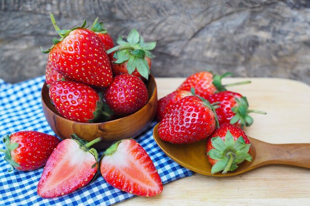 Reife rote Erdbeeren in den hölzernen Schüsseln auf altem Holztisch