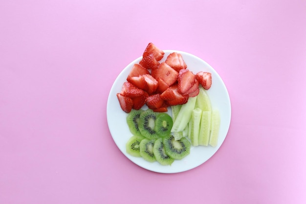 Reife rote Erdbeeren und Kiwi auf einem Teller auf farbigem Hintergrund