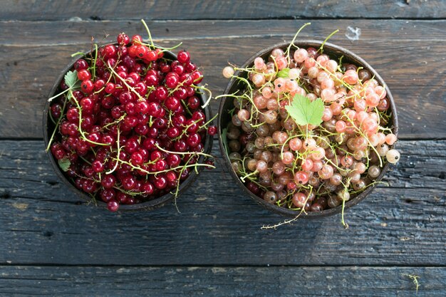 Reife rote Johannisbeeren in einer Schüssel auf rustikalem Holzhintergrund