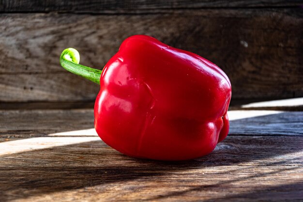 Reife rote Paprika auf einem hölzernen Küchentisch.