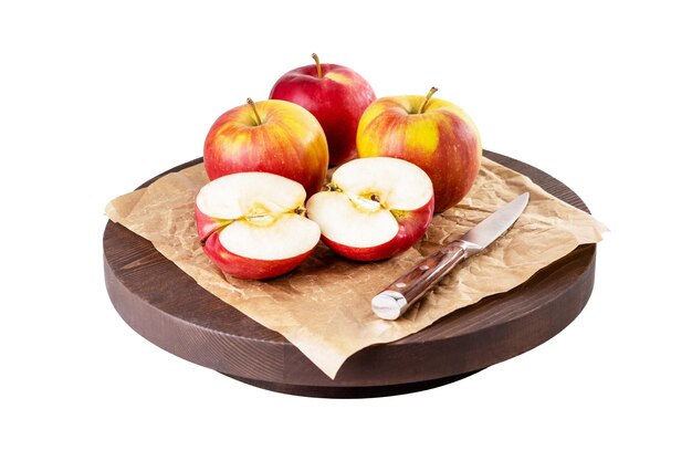 Reife rote Äpfel auf rundem Holzbrett, isoliert auf weiss