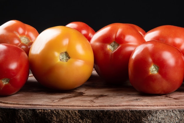 Reife rote Tomate auf Holz mit schwarzem Tisch.