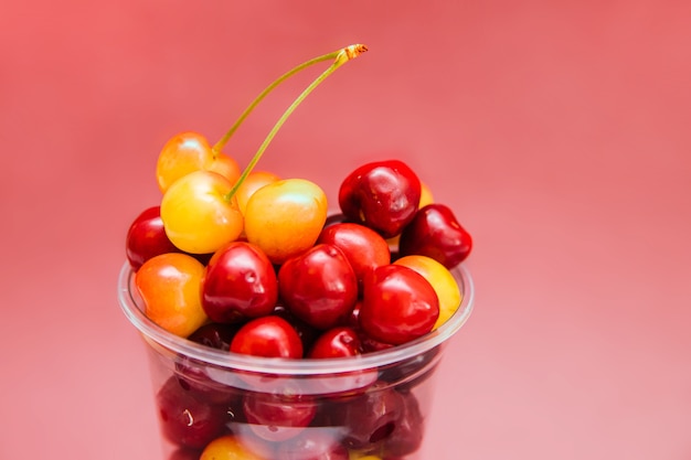 Reife rote und gelbe Kirschen in einem Plastikbecher. Leichter Snack. Obstsalat zum Frühstück. Diät.