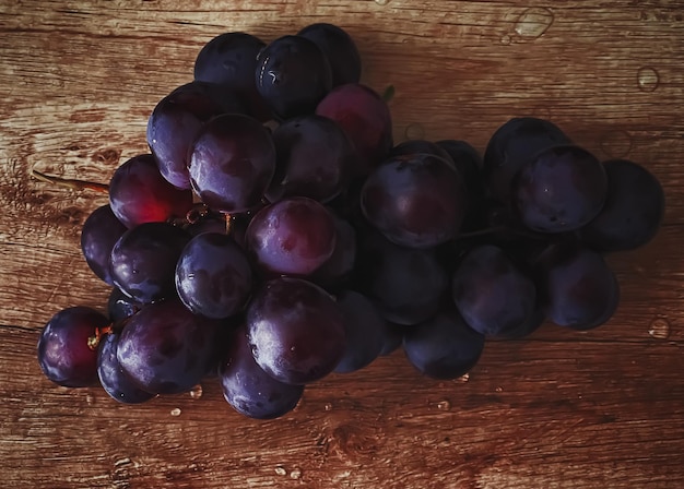 Reife saftige dunkle Trauben auf hölzernen Tischlebensmitteln und Weinbiofrüchten