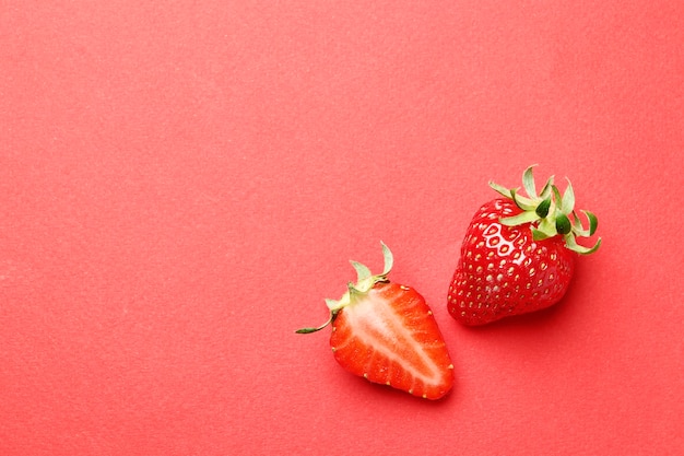 Reife saftige Erdbeeren auf rotem Grund. Muster. Kreative Sommerhintergrundkomposition mit Erdbeere. Minimales Fruchtkonzept.