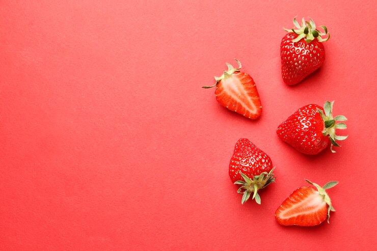Reife saftige Erdbeeren auf rotem Grund. Muster. Kreative Sommerhintergrundkomposition mit Erdbeere. Minimales Fruchtkonzept.