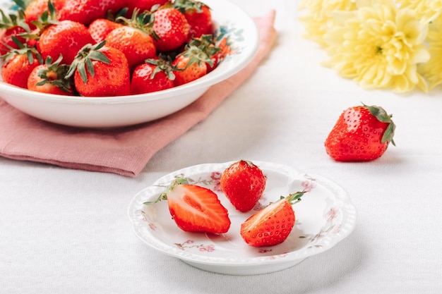 Reife saftige Erdbeeren in Tellern auf einer weißen Tischdecke auf dem Tisch